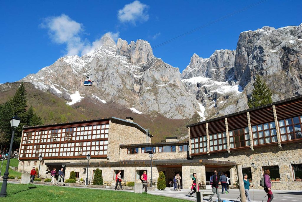 The rustic exterior of Parador de Fuente De nestled at the base of the massive gray mountain walls in Cantabria, Spain.