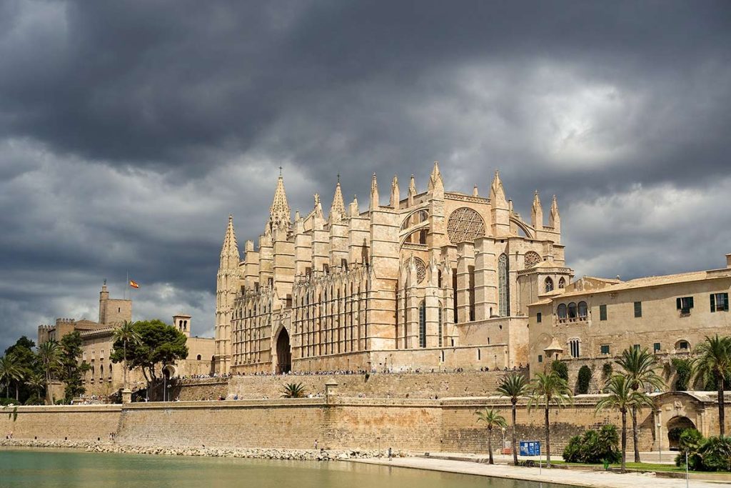 The Gothic Mallorca Cathedral in Palma under dramatic storm clouds during a Mallorca itinerary trip.